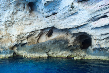 View of caves in the rocks on the blue waters of the Mediterranean Sea in Greece