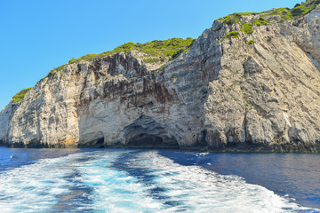 Gray rocks on the blue waters of the Mediterranean Sea in Greece. Motorboat traces on the water