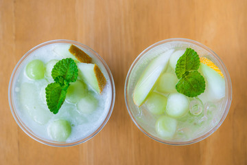Cold fresh melon smoothies with mint in glass, summer drink beverage, healthy food concept, freshness, exotic fruits, Melon smoothies with slices of melon on the wooden table.