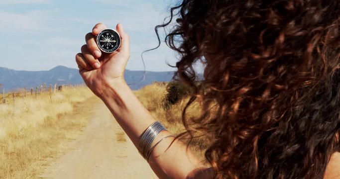 
Detail of a woman holding a compass in her hand on a dirt road. Concept: adventure, travel, self-knowledge