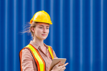 Happiness Female engineer in hard hat and safety vest holding a tablet, Factory worker woman at container cargo