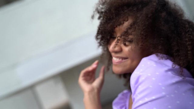 happy and joyful black woman with charming curly hair is smiling and dancing