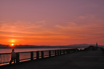 港で夕日を眺める紳士