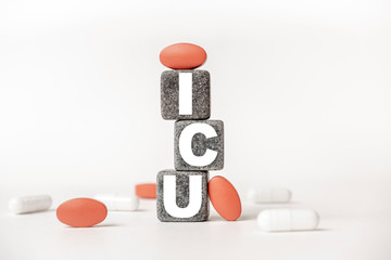 a group of white and red pills and cubes with the word ICU Intensive care unit on them, white background. Concept carehealth, treatment, therapy.