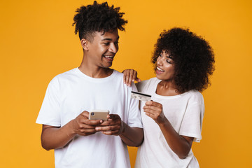 Image of african american couple holding credit card and smartphone