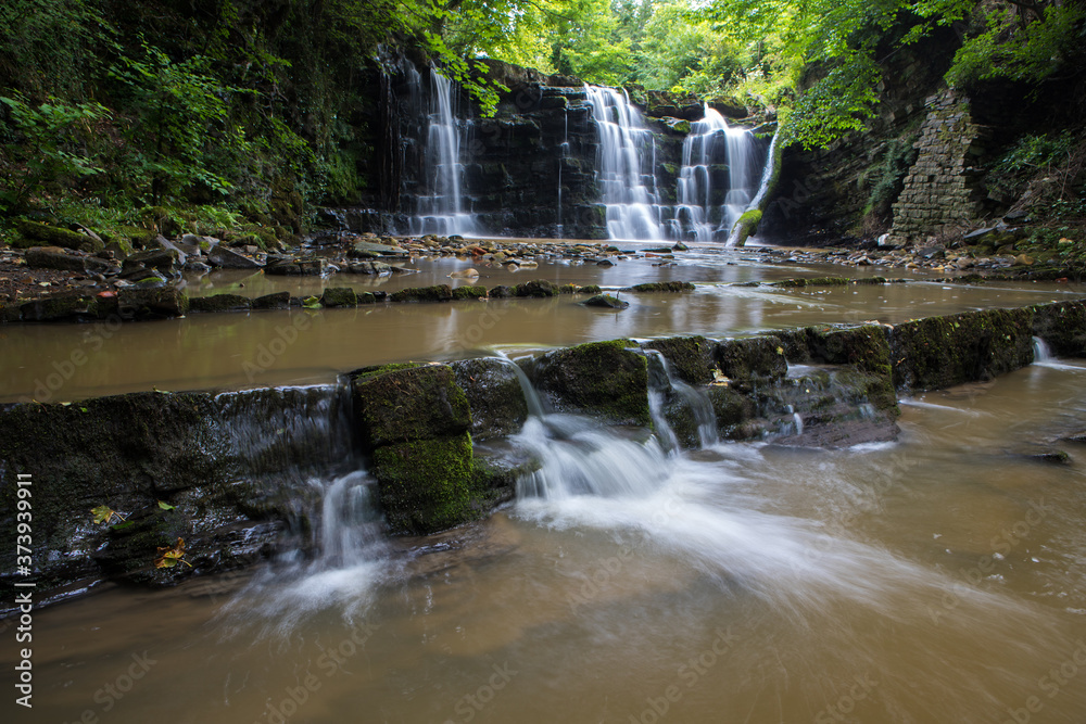 Wall mural hidden waterfall in a deep gorge with trickling white water. forest of bowland, ribble valley, lanca