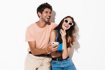 Image of attractive joyful couple laughing while using cellphone