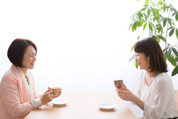 飲み物を飲みながら談笑するミドル女性