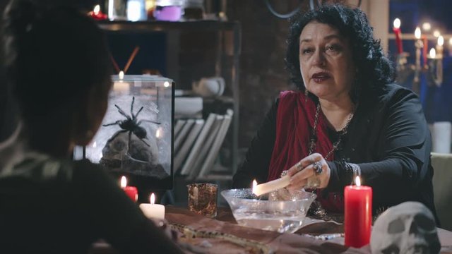 Seer foreseeing future of young woman using candle wax and water