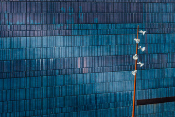 Abstract image of a blue building with a modern light post. Exterior architectural detail of industrial office building. Background and textures. Industrial art and detail.