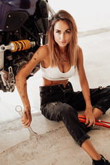Fototapeta na wymiar Female cute technician and modern sport motorbike in bright garage