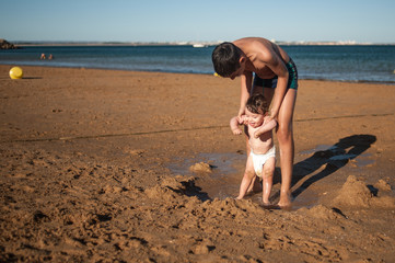 Front view of an older boy playing at the beach with his little toddler brother.Great copy space