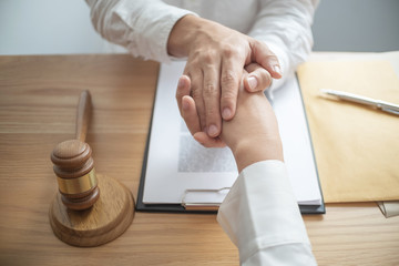 Consultant lawyer holding client hand with trust commitment.