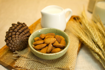 The almonds are in a small bowl, next to the pine cones, a jug