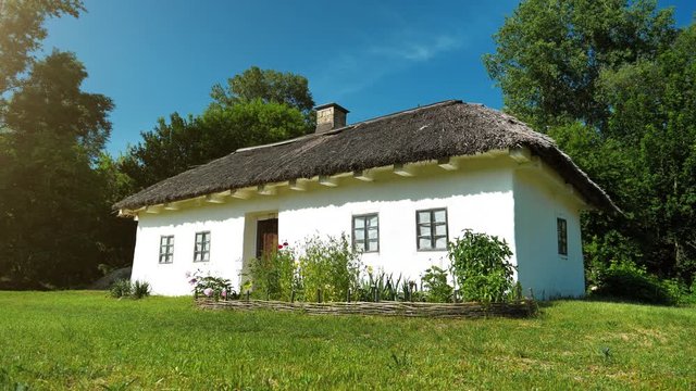 Old white Ukrainian hut with thatch roof in the settlement