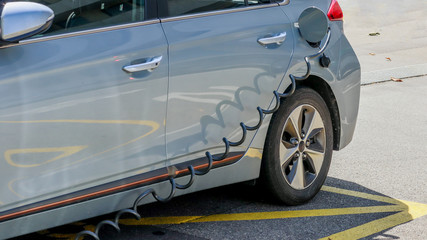 EV Car or Electric car at charging station with the power cable supply plugged in. Eco-friendly alternative energy concept.