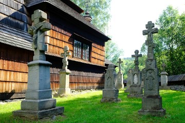 Fototapeta na wymiar Beautiful historic wooden former lemko church in the village of Kotan on a sunny morning. Stone crosses next to it. Low Beskids Mountains, Poland