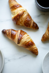 Coffee and croissant on white marble background. French breakfast. Top view flat lay with copy space