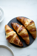 Coffee and croissant on white marble background. French breakfast. Top view flat lay with copy space