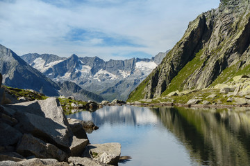 Bergsee mit Spiegelung eines Gebirges im Hintergrund in Tirol Österreich