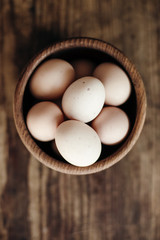 Organic eggs in wooden plate on wooden table.