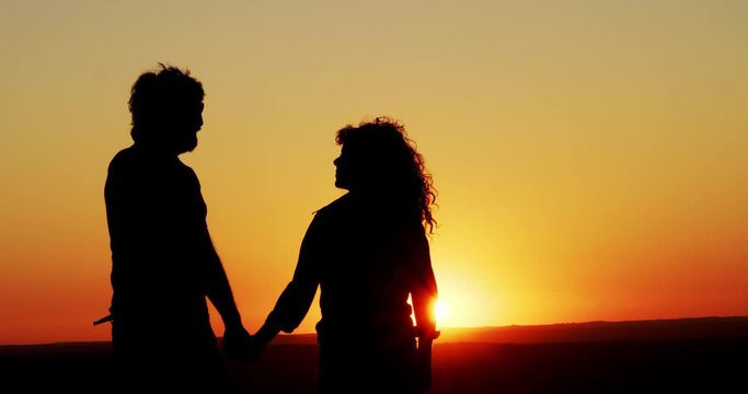 Silhouette of a couple in love holding hands during a sunset on a mountain. Concept. Valentine's Day