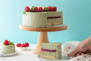 Pistachio mousse cake, cheesecake with fresh raspberry on white plate with mint leaves