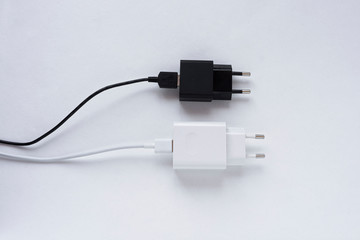 Fototapeta premium Black and white charger with a plug on a white background, charger with a block, for a smartphone, top view