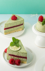 Pistachio mousse cake, cheesecake with fresh raspberry on white plate with mint leaves