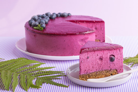 Blueberry mousse cake, cheesecake with fresh blueberry  on white plate with mint leaves. Tasty homemade cheesecake