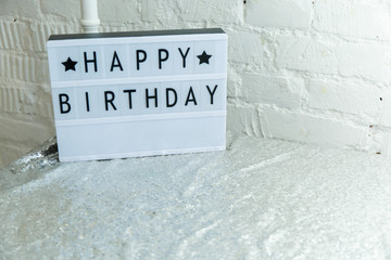 
plastic white nameplate with happy birthday lettering on silver tablecloth