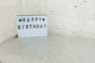 
plastic white nameplate with happy birthday lettering on silver tablecloth
