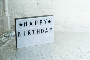 
plastic white nameplate with happy birthday lettering on silver tablecloth