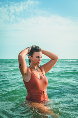 Beautiful young European woman with an orange swimsuit at the sea in Cádiz