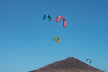 Power kites flying above the mountain, used by kitesurfers to ride the waves at one of the windiest beaches on the island, Montana Roja, El Medano, Tenerife, Canary Islands, Spain