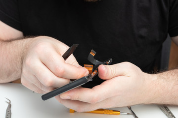 Men's hands repair a mobile phone, install spare parts