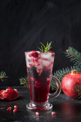 Pomegranate Holiday cocktail with rosemary sprig, sparkling wine on black.