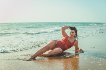 Beautiful young European woman with an orange swimsuit on a beach in Cádiz