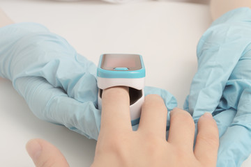 Assessment of the function of the respiratory system.  The doctor in the clinic measures the blood saturation and pulse in the patient with a pulse oximeter