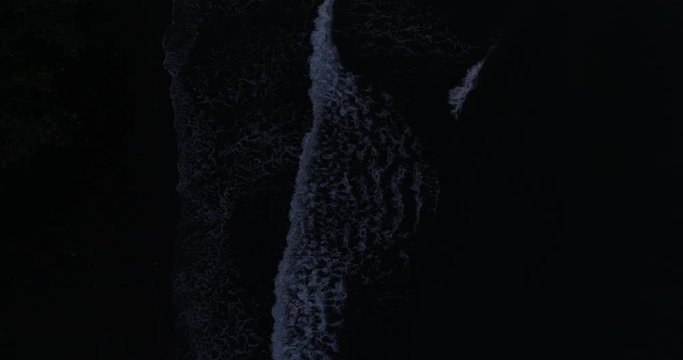 Overhead drone shot of waves breaking on a beach at night