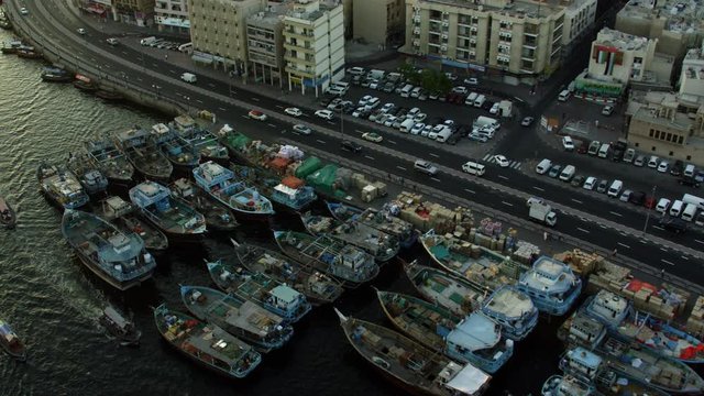 A close up view of Deira's Old Souq Marine Transport Station by the creek tilting down to Dhow boats docked side by side, Aerial, 6-axis stabilized gimbal, Shotover F1, 8K, parallax.