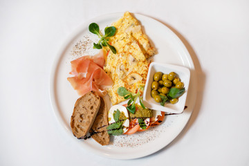 Omelet with croutons, bacon, tomatoes, olives, garnished with soy sauce, mustard and basil. The concept of a delicious hearty homemade breakfast served in a restaurant.