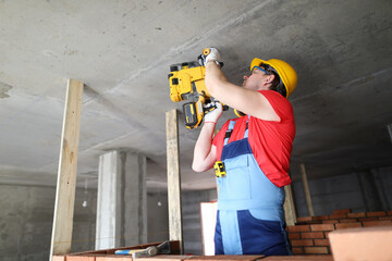 Builder works with special equipment on ceiling
