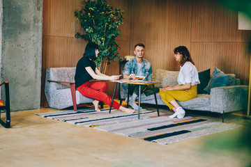 Meeting of professional designers in modern apartment interior, casual dressed male and female colleagues collaborating on common project having brainstorming course for productive developing