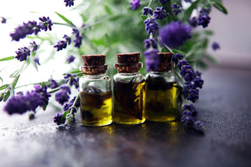 lavender oil in a glass bottle on a background of fresh flowers.