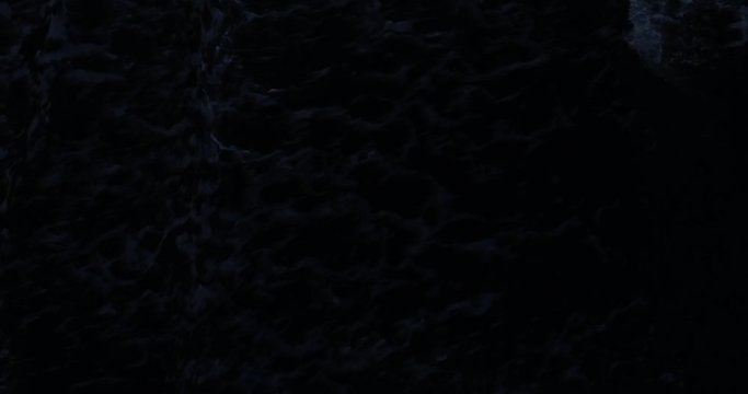 Overhead drone shot of dark waves breaking on beach at dusk