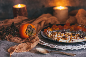 Healthy breakfast concept. Oatmeal granola with yogurt, dried fruit, seeds, honey, persimmon in bowl over grey concrete background. Allergy-friendly, gluten free concept