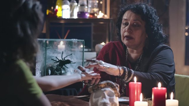 Old seer reading lines in hand of young woman client