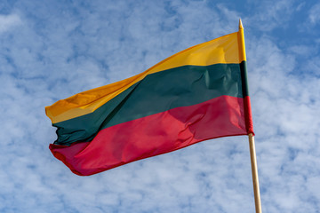 Lithuanian national tricolor flag waving in a beautiful cloudy sky.