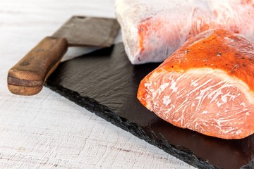 Frozen raw pork neck chops meat steak isolated on slate. Frozen uncooked slices of beef steaks, tenderloin or rib eye with ice crystals on it.